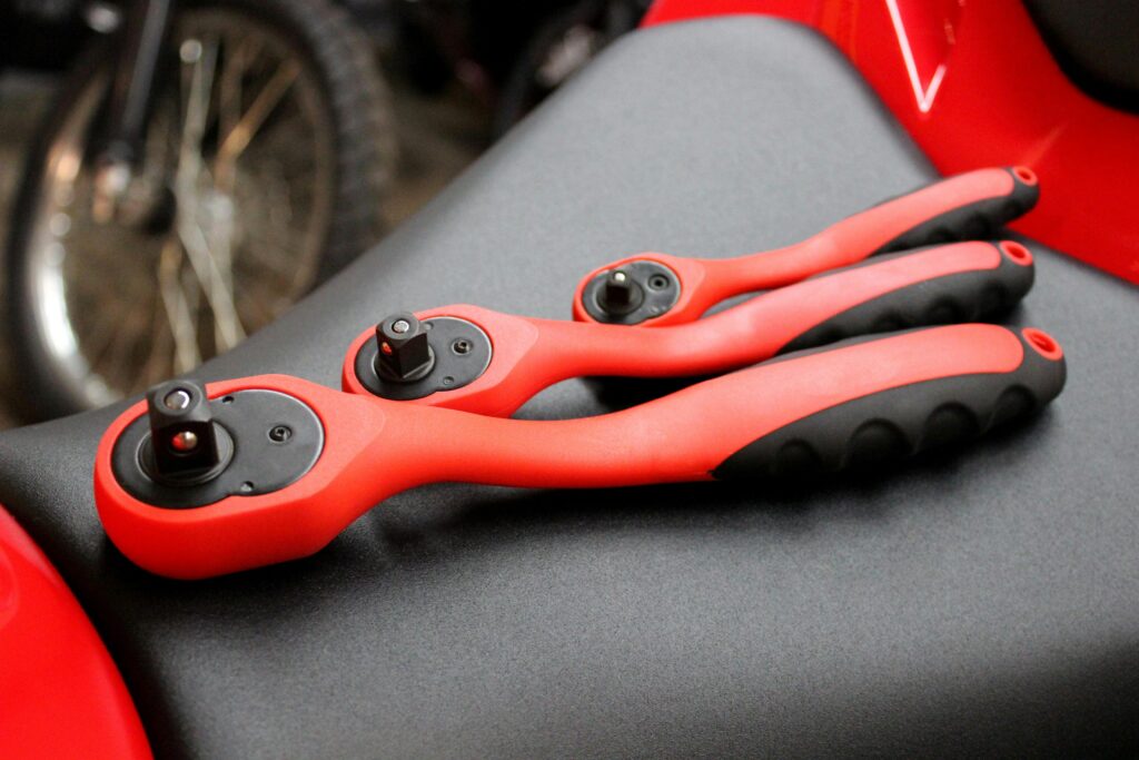 Close-up of red and black socket wrenches on a motorcycle seat.