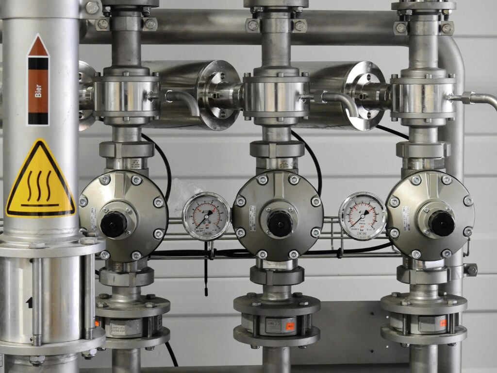 Close-up of stainless steel pipes with pressure gauges in an industrial setting.